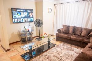 プレトリアにあるPremium Getaway @ la Bella Costaのソファとガラスのテーブルのあるリビングルーム