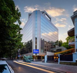 a tall glass building with a sign on it at Rosslyn Thracia Hotel Sofia in Sofia +49 photos