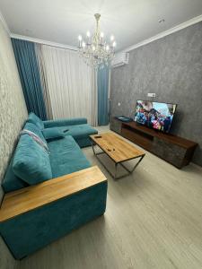 a living room with a blue couch and a table at Bahor Yunusabad Lux in Tashkent