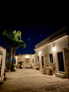 a house with a patio at night with a palm tree at Villa La Rosa in Chiaramonte Gulfi