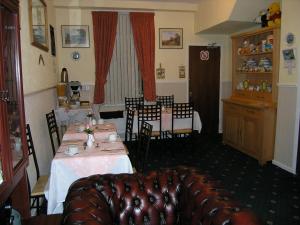 uma sala de jantar com uma mesa e cadeiras e um sofá em Springfield B&B em Belfast