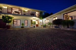 a large white house with a brick driveway at night at Candlewood Lodge in Knysna
