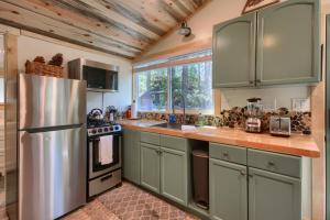 La cuisine est équipée d'armoires vertes et d'un réfrigérateur en acier inoxydable. dans l'établissement Beetlebark Bungalow- Inside Yosemite w/ hot tub EV charging cable, à North Wawona 15 autres photos