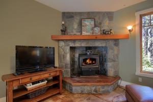 ein Wohnzimmer mit einem Steinkamin, einem TV und einem Herd in der Unterkunft Aspen House in Fish Camp- 2 Miles from Yosemite's South Entrance in Fish Camp