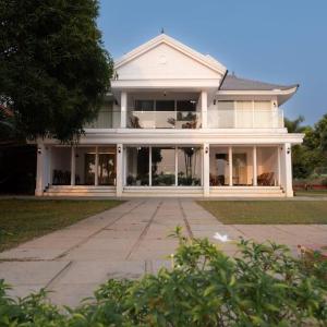 a large white house with a lot of windows at Riveria Portico - River side 6 bedroom private pool Bungalow in Parūr