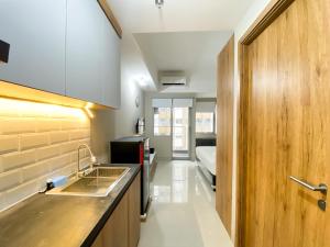 ブカシにあるMinimalist Studio Room Gateway Park LRT City Jatibening Apartment By Travelioのシンク付きのキッチンとベッドが備わった部屋