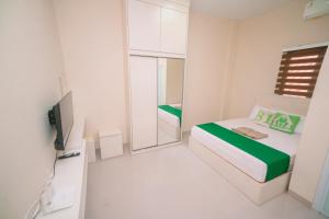 ナゴヤにあるHomestay81 Penuinのベッド1台、テレビが備わる小さな白い客室です。