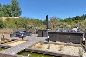 a wooden deck with a pool of water and some chairs at Entre dunes et pins in Merlimont