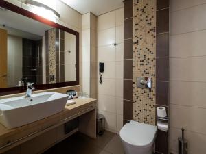 a bathroom with a sink and a toilet and a mirror at Elektra Stay Port & Sea View in Kalamata