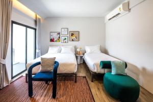 a bedroom with a bed and a chair and a window at claybed chiangrai in Ban San Ton Ko (1)