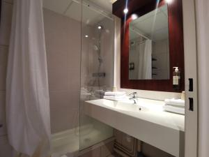 ein Badezimmer mit Waschbecken und Dusche mit Spiegel in der Unterkunft Hôtel Le Mercator in Vendôme