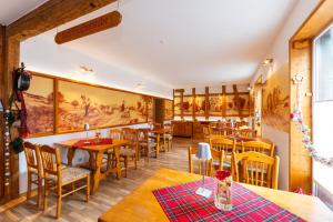 a restaurant with wooden tables and chairs and paintings on the wall at Pension Zum Schotten in Zella-Mehlis