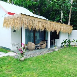 a house with a straw roof and chairs and flowers at Rg real state 3 in Kuta Lombok