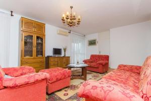una sala de estar con muebles de color rojo y una lámpara de araña. en Sunny Apartment, en Omiš