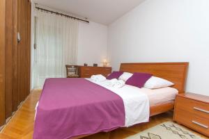 1 dormitorio con 1 cama grande con sábanas moradas en Sunny Apartment, en Omiš