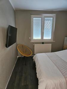 a bedroom with a bed and a chair and a window at La Sauvagerie in Le Portel