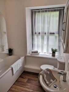 a bathroom with a sink and a tub and a window at Estuary View Bank House Stunning apartment in Millom