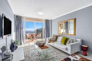 a living room with a couch and a large window at The Waves 302 in Bloubergstrand