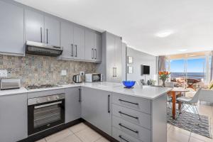 a kitchen with white cabinets and a view of the ocean at The Waves 302 in Bloubergstrand
