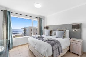 a bedroom with a large bed and a large window at The Waves 302 in Bloubergstrand