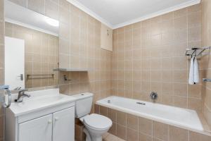 a bathroom with a toilet and a tub and a sink at The Waves 302 in Bloubergstrand +17 photos