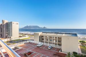 a view of a building with the ocean in the background at The Waves 302 in Bloubergstrand