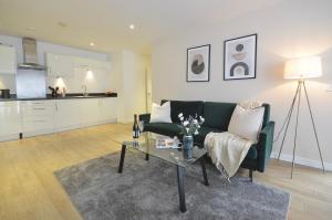 a living room with a green couch and a table at Modern 2 Bedroom Apartment Steps from Vauxhall St in London