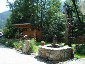 einen Steinbrunnen in einem Garten mit einer Bank in der Unterkunft Jörghof in Bad Kleinkirchheim