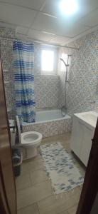 a bathroom with a toilet and a tub and a window at Appartement Spacieux fonctionnel Parking assuré!! in Novelda