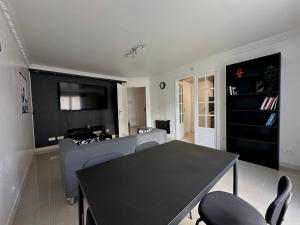 a living room with a black table and chairs at Appartement Confort à Louvres proche CDG in Louvres