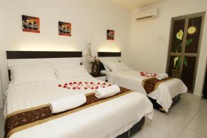 a bedroom with two beds with red roses on them at New Century Hotel Melaka in Malacca