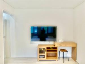a tv on a wall with a desk and a stool at Kelly House in Goyang