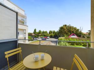 a table and chairs on a balcony with a view of a street at À 150m de la plage, appartement mezzanine pour 4 in Les Bussolleries