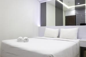 a bedroom with a white bed with two slippers on it at Comfort 2BR Apartment at 30th Floor Transpark Cibubur By Travelio in Depok