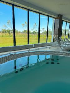 einen Pool mit 2 Stühlen und Fenstern in der Unterkunft Brand-New Apartment EYE ON BALTIC SEA Luxurious Spa Escape in Dziwnów with Stunning Views in Dziwnów