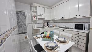 a kitchen with white cabinets and a table with food on it at VILA STATION - Apartamento familiar en la costa gallega in Vilagarcia de Arousa