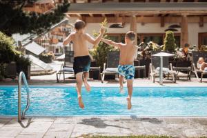 two young boys jumping into a swimming pool at Hotel Gaspingerhof in Gerlos