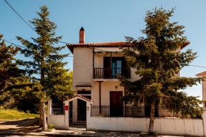 a white house with a fence and a tree at Ilia house in Volos