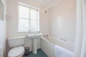 a white bathroom with a toilet and a sink at Chestnutt Cottage, Reydon in Reydon +20 photos
