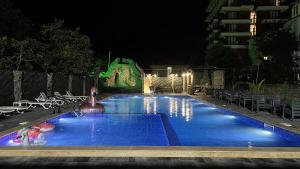 una piscina notturna con un edificio sullo sfondo di Grand Hotel Kobuleti a Kobuleti