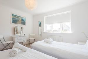 a white bedroom with two beds and a desk at Chestnutt Cottage, Reydon in Reydon