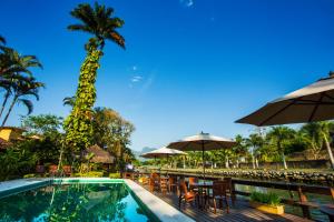 una piscina con sombrillas, mesas y sillas en Pousada Corsario Paraty en Parati