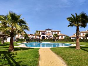 a swimming pool with palm trees in front of a house at RELAX en Vera Playa con SPA con Ventiladores de techo y aire acondicionado in Vera