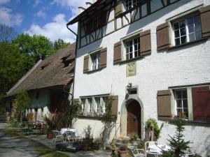 ein großes weißes Gebäude mit Tischen und Stühlen davor in der Unterkunft Burghof Wallhausen in Konstanz