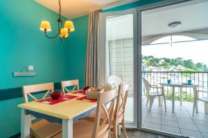ein Esszimmer mit einem Tisch und Stühlen sowie einem Balkon in der Unterkunft Le Tamm Bara - Appt avec piscine partagée in Douarnenez