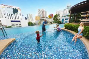 バンコクにあるThe Rich Residence Sukhumvit Nanaのプールでボールで遊ぶ家族