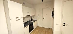 a kitchen with white cabinets and a stove top oven at Lux Beach Apartment BLACK in Lido di Ostia