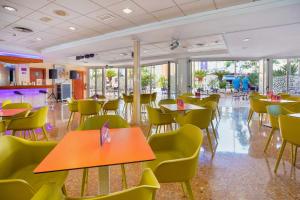 restauracja ze stołami, krzesłami i oknami w obiekcie Hotel Servigroup Nereo w mieście Benidorm