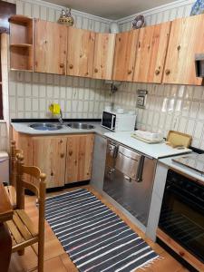 a kitchen with wooden cabinets and a sink and a microwave at Acogedora casa a pie de playa in Cillero
