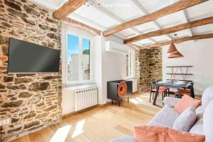 a living room with a stone wall with a flat screen tv at Lover's Lane 1, TerreMarine in Riomaggiore